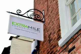 Extra Mile Digital hanging shop sign on red brick building