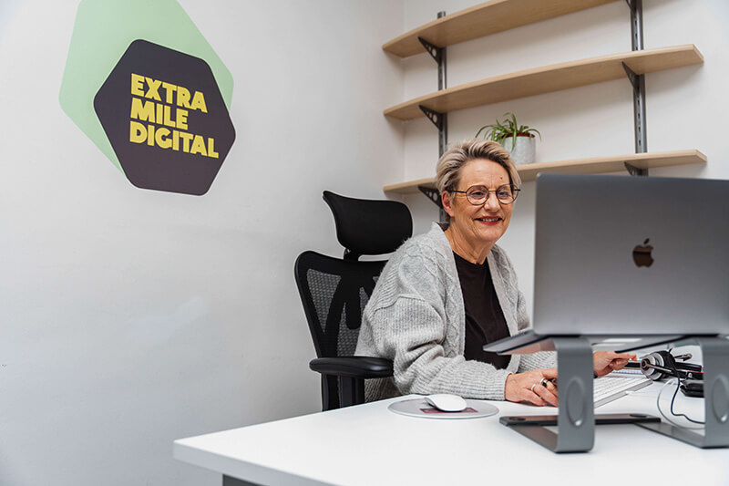 A happy woman working on her computer at ExtraMile Digital
