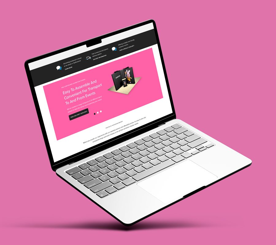 Open laptop on a pink background, displaying a webpage from the Print Designs website.