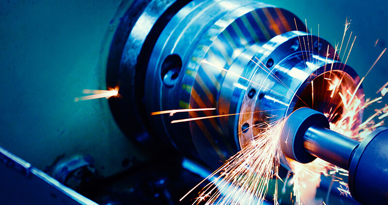 Close-up of a CNC metalworking machine creating sparks while grinding a metal component