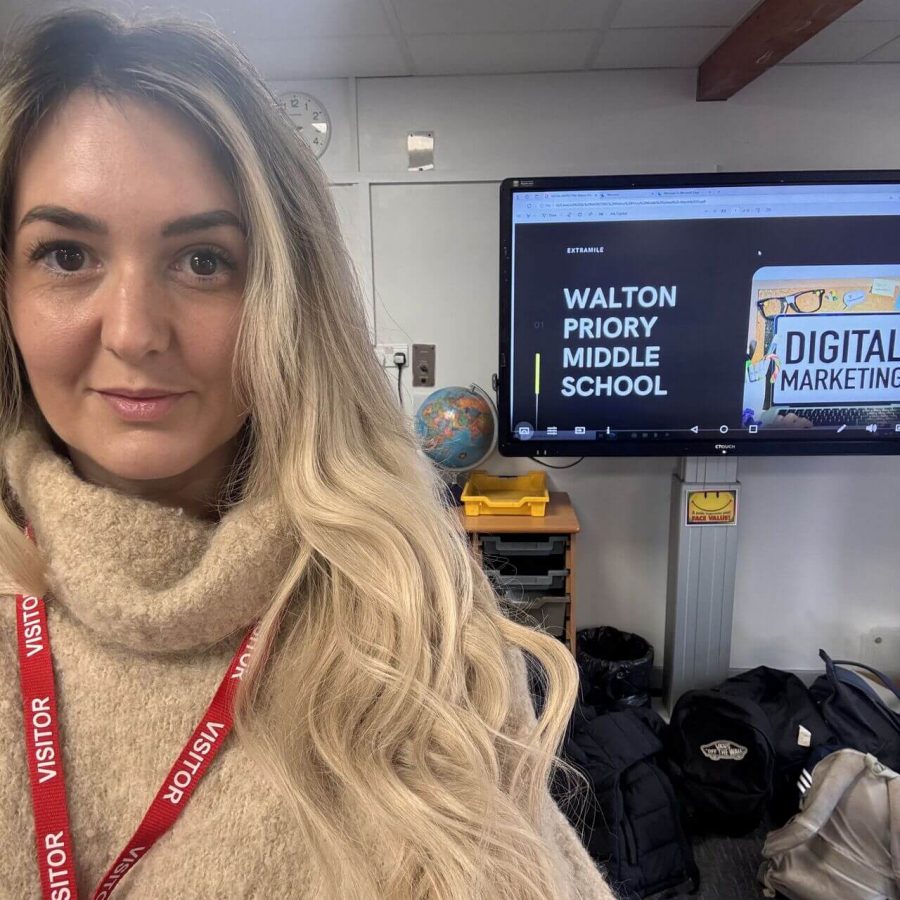 Woman smiling in front of Walton Priory school digital marketing display